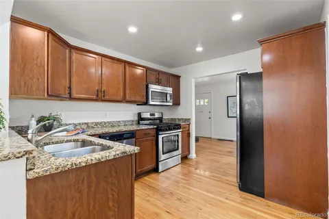a kitchen with granite countertop stainless steel appliances a sink a stove a refrigerator cabinets and a counter top space