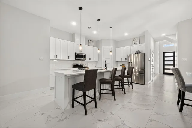 a kitchen with stainless steel appliances kitchen island a table chairs sink and cabinets