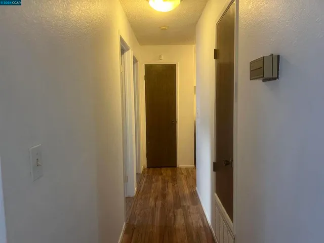 a view of a hallway with wooden floor and a bathroom