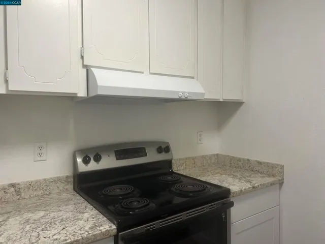 a kitchen with granite countertop white cabinets and a stove