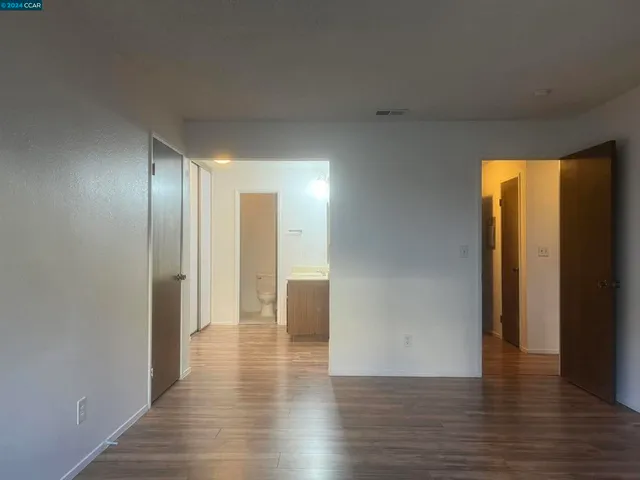 a view of hallway with an empty room and wooden floor