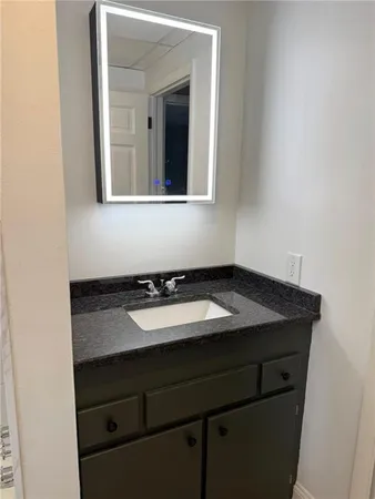 a bathroom with a granite countertop sink and a mirror