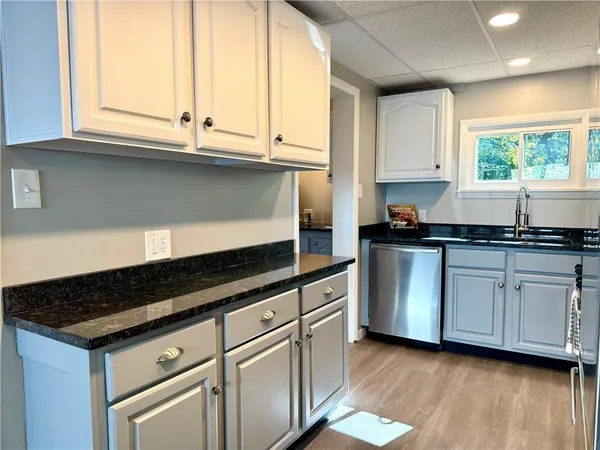 a kitchen with granite countertop white cabinets and a sink