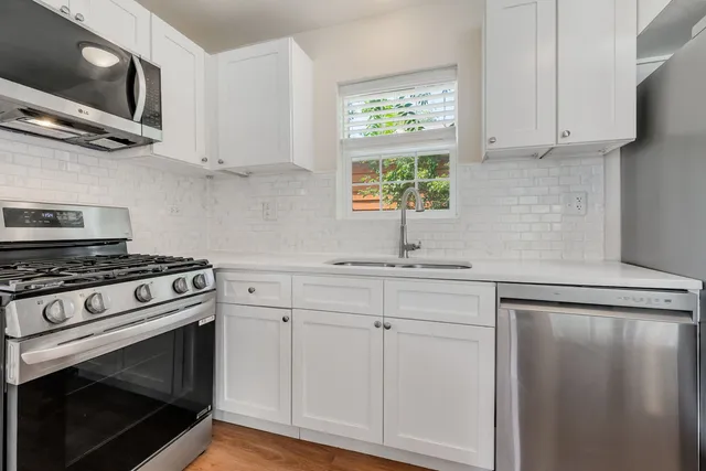 a kitchen with stainless steel appliances white cabinets and a stove top oven