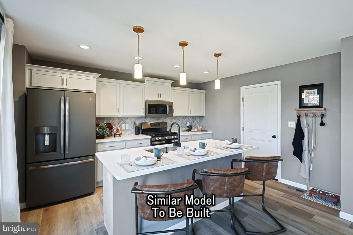 White Oak Plan At Woodlyn Preserve Selinsgrove, PA 17870 - Photo 12 of 42 a kitchen with stainless steel appliances a refrigerator a stove a sink a dining table and chairs