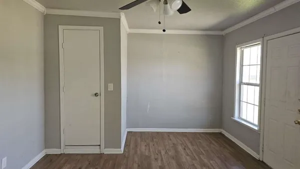 an empty room with wooden floor closet and windows