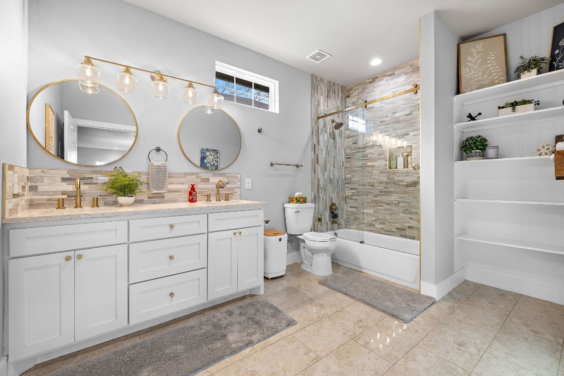 611 Elliott Street Taylor, TX 76574 - Photo 20 of 29 a spacious bathroom with a double vanity sink toilet mirror and shower