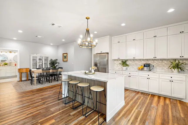 a kitchen with stainless steel appliances granite countertop a white cabinets counter and chairs