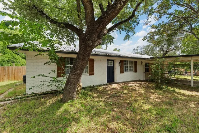 a view of a house with a large tree and a yard