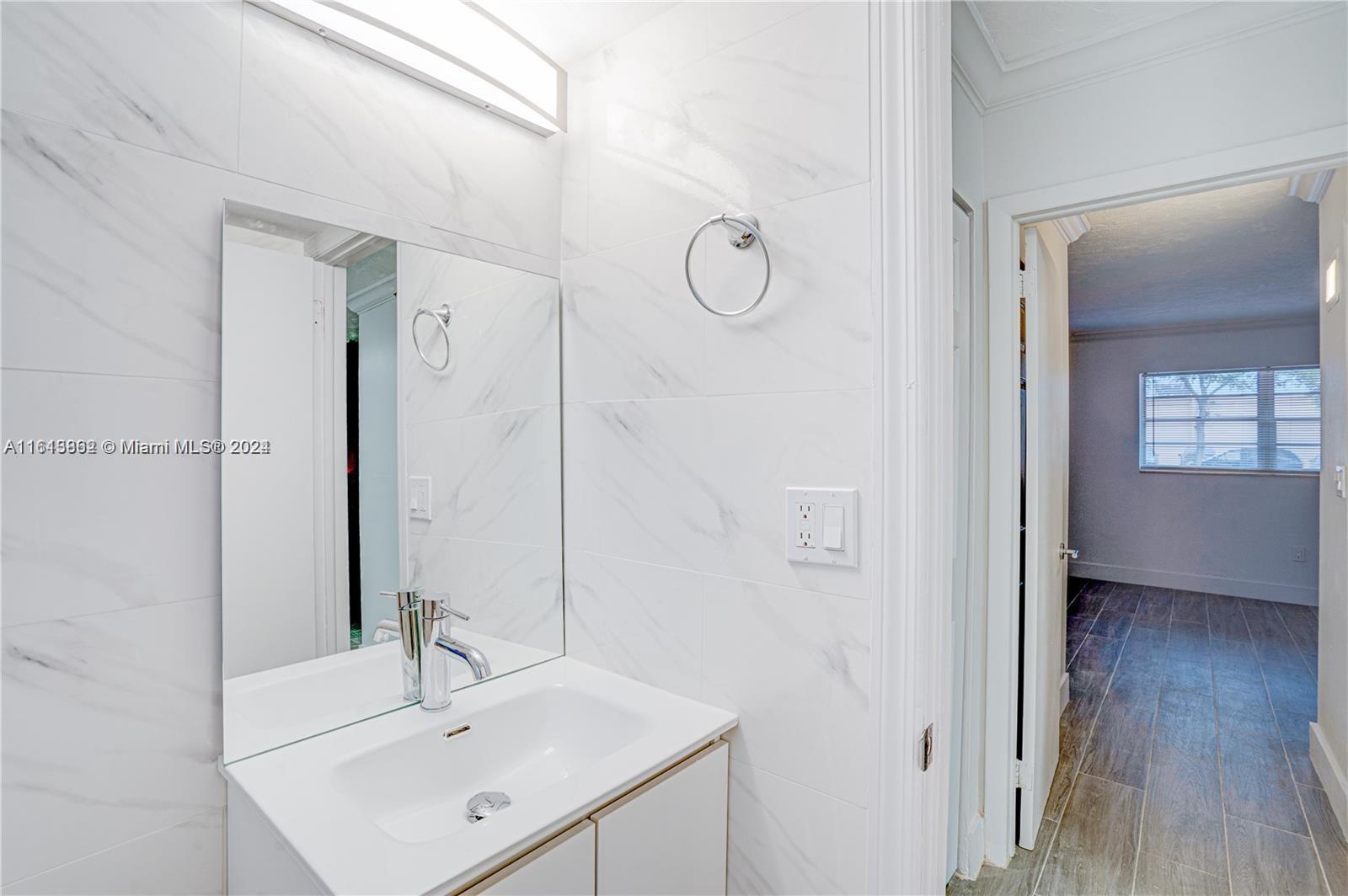 3019 Southwest 68th Terrace, Unit 6 Miramar, FL 33023 - Photo 5 of 10 a bathroom with a sink a mirror and shower
