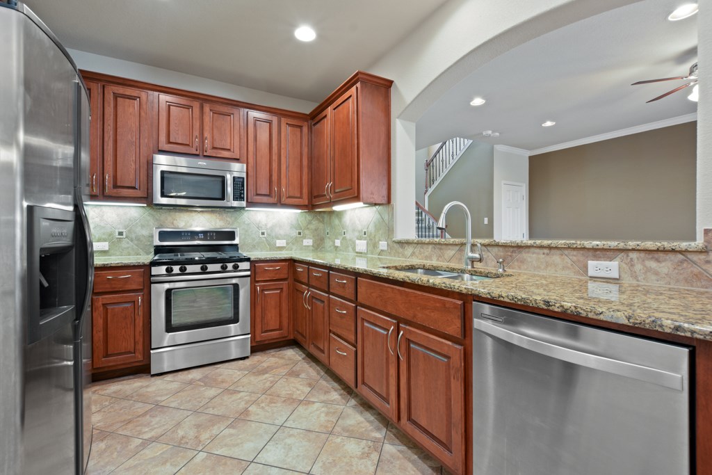 a kitchen with stainless steel appliances granite countertop a sink and stove top oven