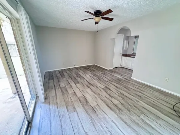 a view of empty room with wooden floor and fan
