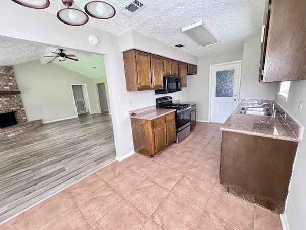 a living room with furniture a flat screen tv and kitchen view