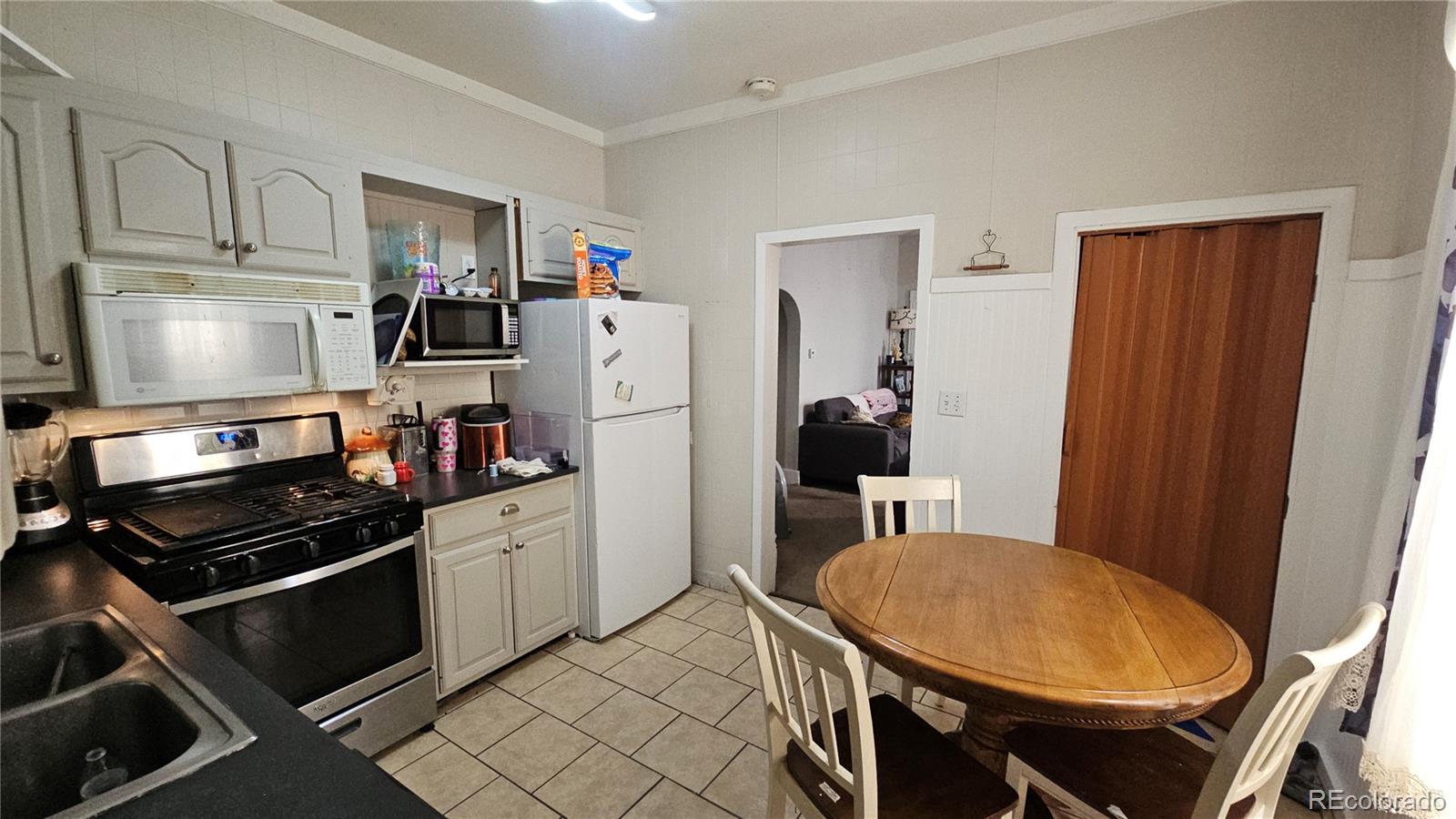 402 East Routt Avenue Pueblo, CO 81004 - Photo 4 of 9 a kitchen with stainless steel appliances a refrigerator a stove a sink and white cabinets