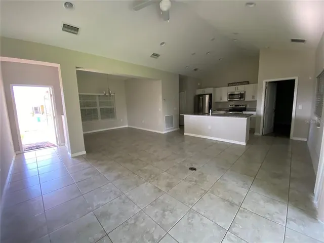 a view of a electric appliances in kitchen and empty room with windows