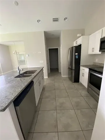 a kitchen with granite countertop a sink cabinets and stainless steel appliances