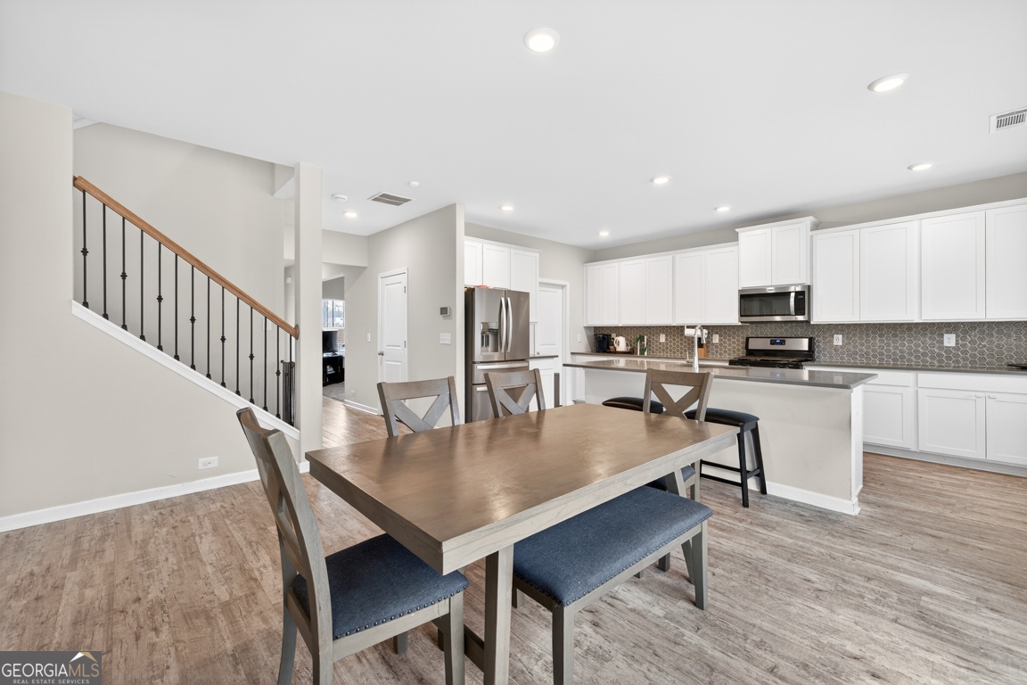 3511 Argent Way Marietta, GA 30008 - Photo 27 of 56 a kitchen with stainless steel appliances granite countertop a stove a refrigerator a kitchen island a dining table and chairs with wooden floor