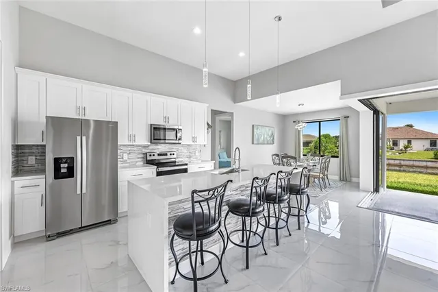 a kitchen with granite countertop a refrigerator a stove a sink a dining table and chairs