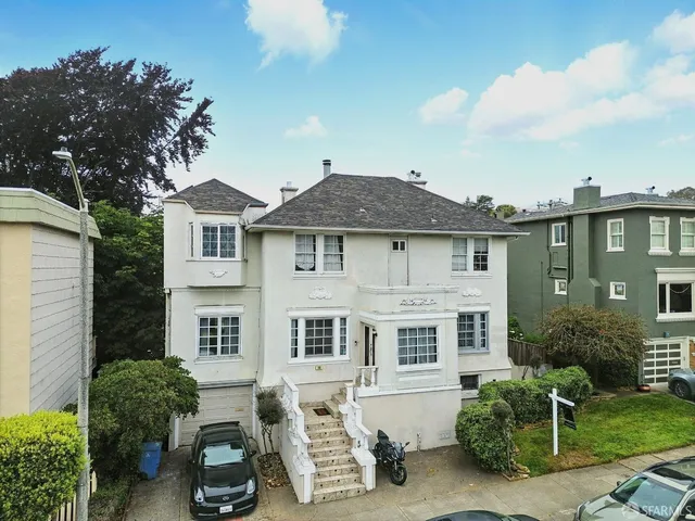 a front view of a house with a yard and potted plants