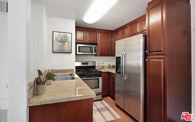 a kitchen with stainless steel appliances granite countertop a refrigerator a stove and a sink with wooden floor