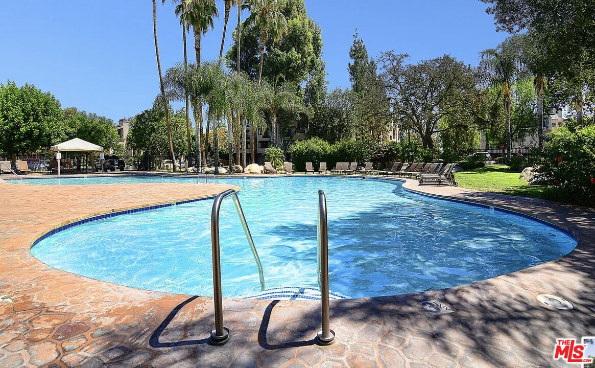 5545 Canoga Avenue, Unit 203 Woodland Hills, CA 91367 - Photo 8 of 12 a view of a swimming pool with a yard and palm trees