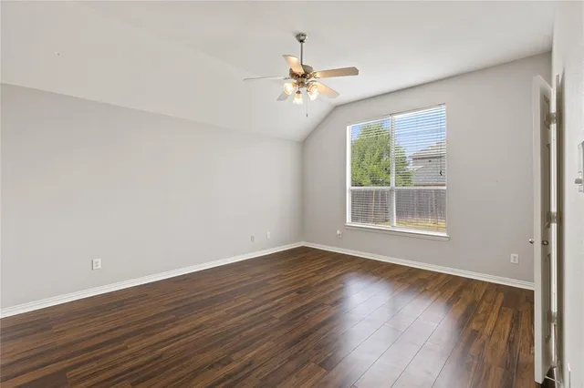 a view of an empty room with wooden floor and a fireplace