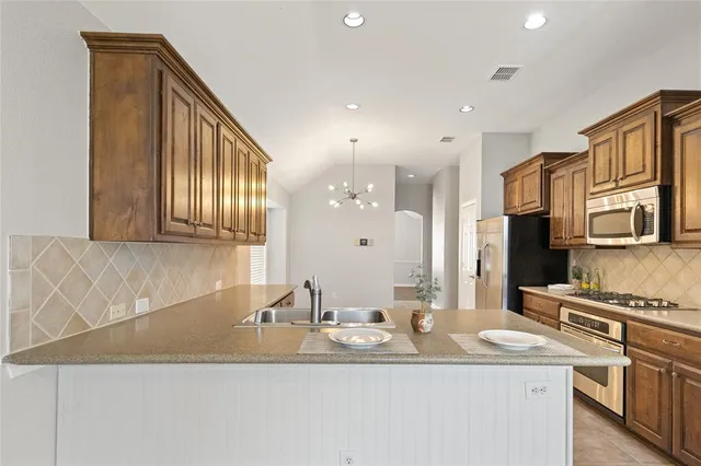 a kitchen with stainless steel appliances granite countertop a sink and a refrigerator