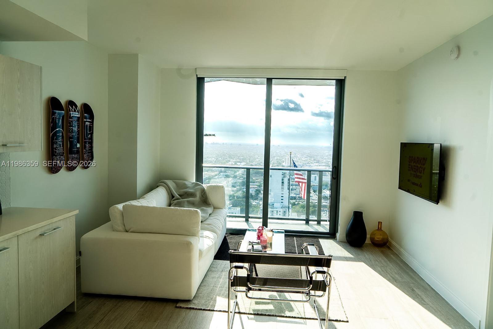 55 Southwest 9th Street, Unit 3607 Miami, FL 33130 - Photo 3 of 15 a living room with furniture and a flat screen tv