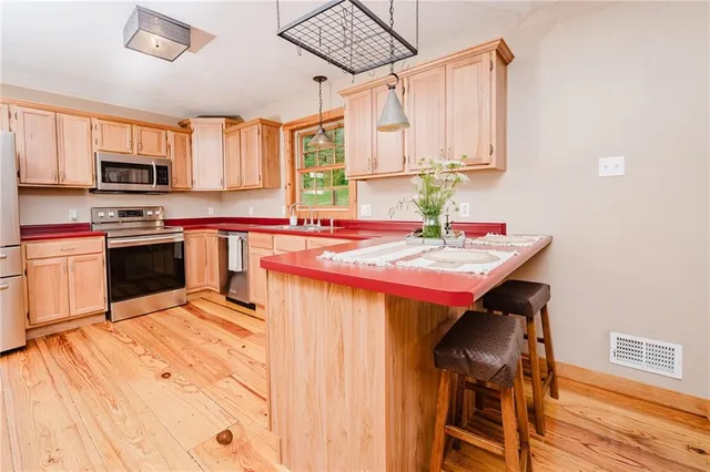 a kitchen with stainless steel appliances kitchen island granite countertop a table chairs sink and cabinets