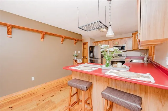 a dining room with stainless steel appliances kitchen island granite countertop a table chairs and a wooden floor
