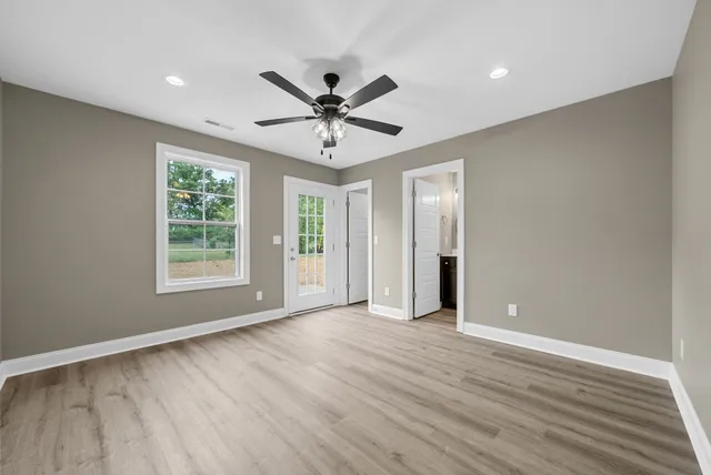 a view of an empty room with a window and wooden floor