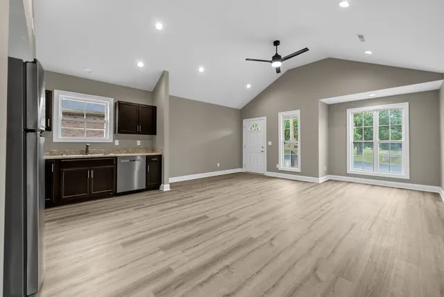 an empty room with wooden floor and a kitchen