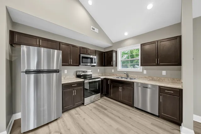 a large kitchen with cabinets stainless steel appliances and a window