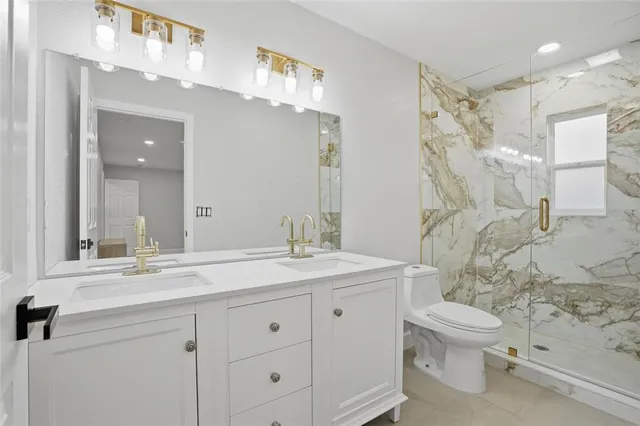 a bathroom with a granite countertop sink a toilet and a mirror