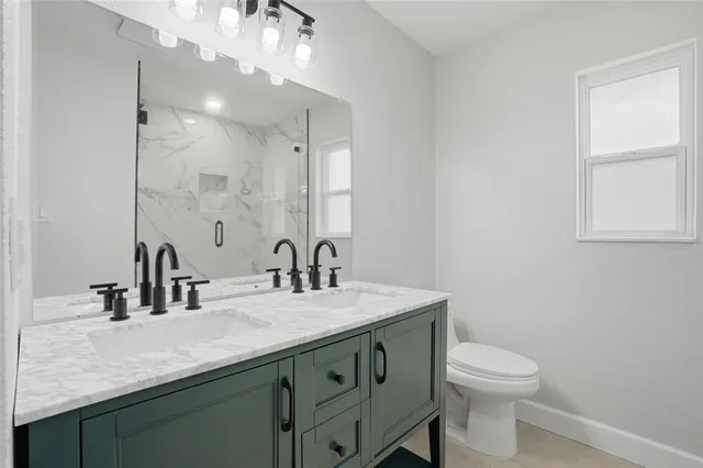 a bathroom with a granite countertop sink a toilet and a mirror