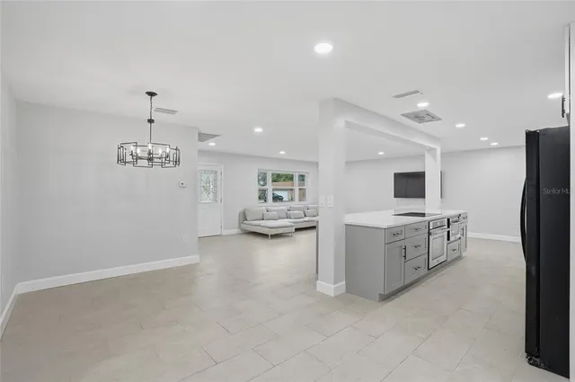 a large white kitchen with a refrigerator a stove a sink and a dining table with wooden floor