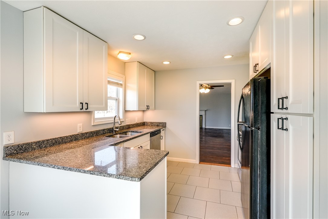 5065 Harper Road Solon, OH 44139 - Photo 14 of 31 Kitchen featuring dark stone countertops, a peninsula, freestanding refrigerator, white cabinets, and a sink