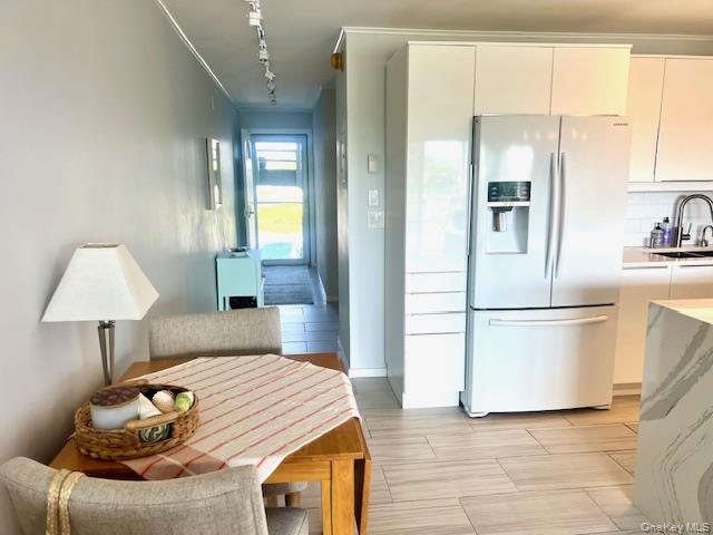 35 Library Avenue, Unit 6J Westhampton Beach, NY 11978 - Photo 13 of 19 Kitchen featuring stainless steel refrigerator with ice dispenser, rail lighting, modern cabinets, and backsplash