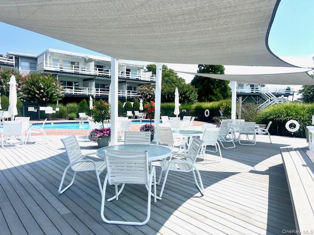 35 Library Avenue, Unit 6J Westhampton Beach, NY 11978 - Photo 18 of 19 Deck with outdoor dining space and a community pool