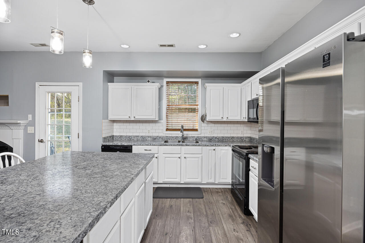 704 Nightshade Way Raleigh, NC 27610 - Photo 17 of 39 a kitchen with granite countertop a sink stove and refrigerator
