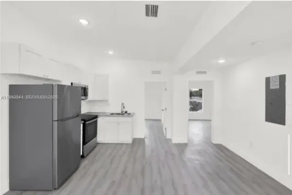 a view of a kitchen with a refrigerator and wooden floor