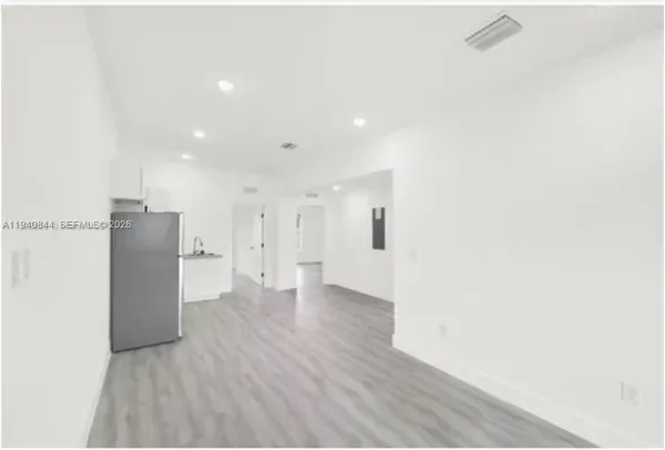 a view of a hallway with wooden floor and a bathroom