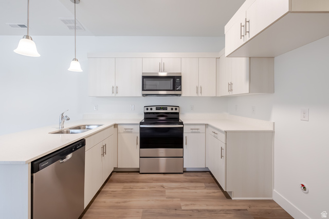 693 West 4500th South, Unit O303 Mapleton, UT 84664 - Photo 11 of 15 Kitchen featuring stainless steel appliances, a peninsula, light wood-type flooring, hanging light fixtures, and white cabinets