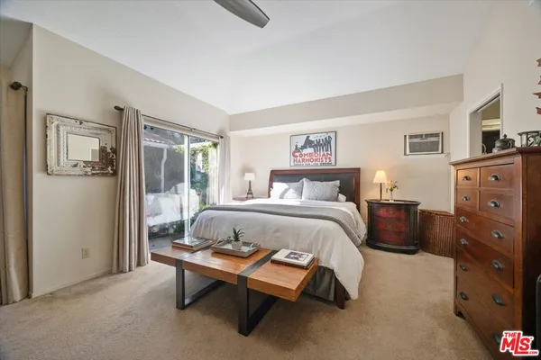 a bedroom with a bed a dresser and a large window