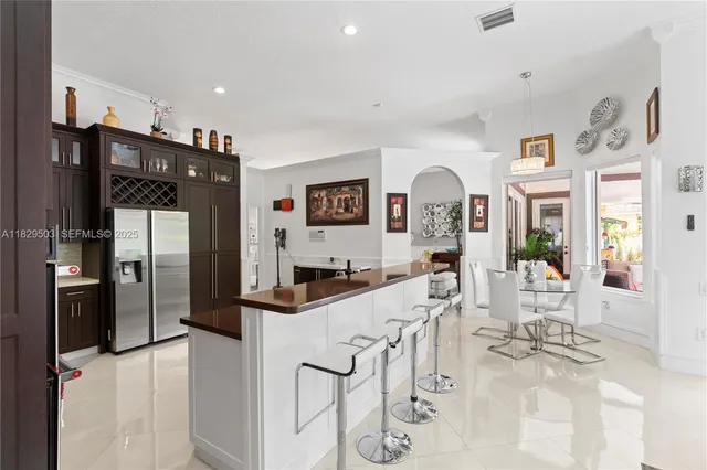 a kitchen with stainless steel appliances kitchen island granite countertop a refrigerator a sink and wooden cabinets