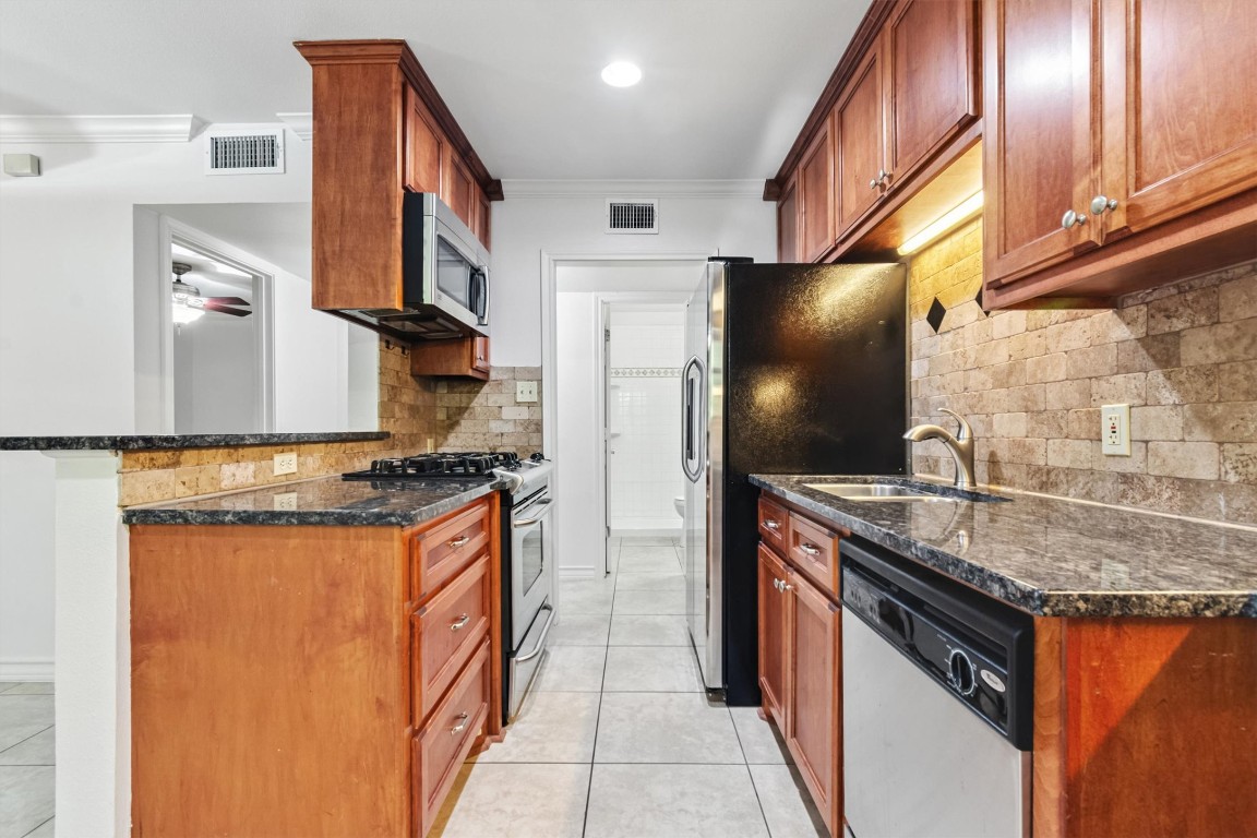 407 East 45th Street, Unit 111 Austin, TX 78751 - Photo 9 of 15 a kitchen with stainless steel appliances granite countertop a sink stove and refrigerator