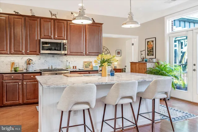 a kitchen with stainless steel appliances granite countertop a refrigerator a stove a sink dishwasher and white cabinets with wooden floor