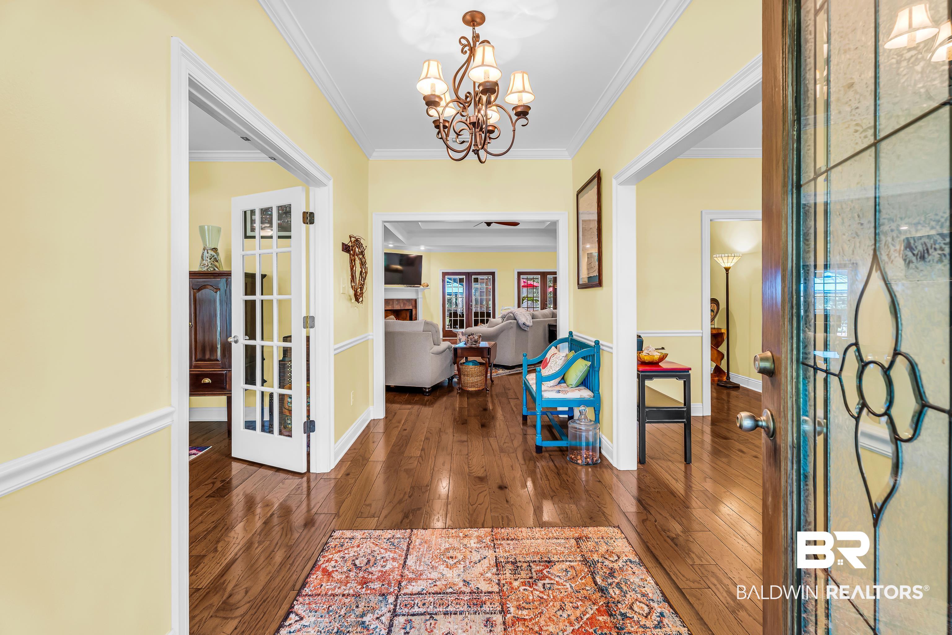 7014 Blakeley Road Daphne, AL 36527 - Photo 19 of 45 Hardwood flooring extends throughout this entry foyer, featuring a decorative chandelier and crown molding