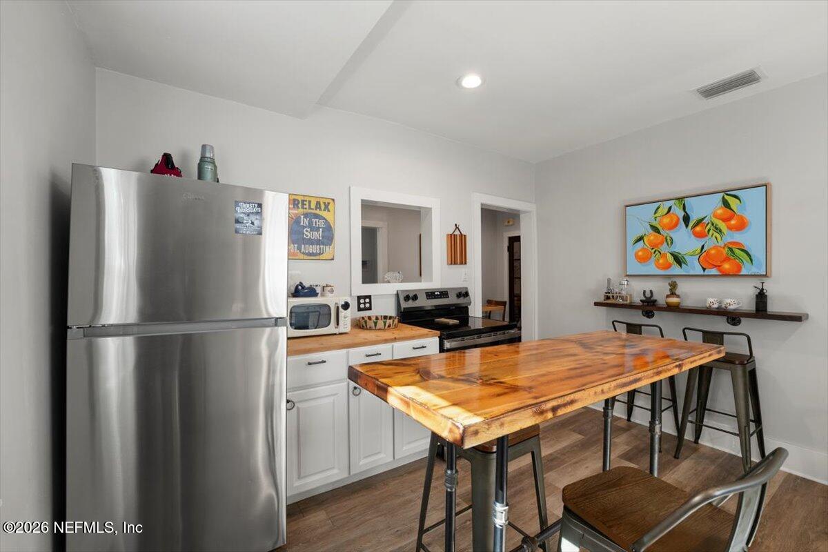 71 Kings Ferry Way St. Augustine, FL 32084 - Photo 10 of 33 a kitchen with stainless steel appliances a refrigerator a stove a dining table and chairs with wooden floor