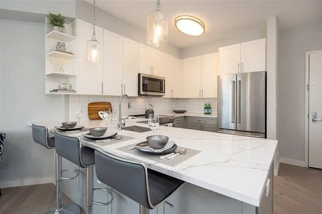 a kitchen with stainless steel appliances a sink a stove a microwave a refrigerator and cabinets